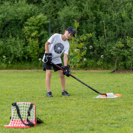 Young hockey player practicing saucer pass with Sauce Combo launch pad and catcher in backyard